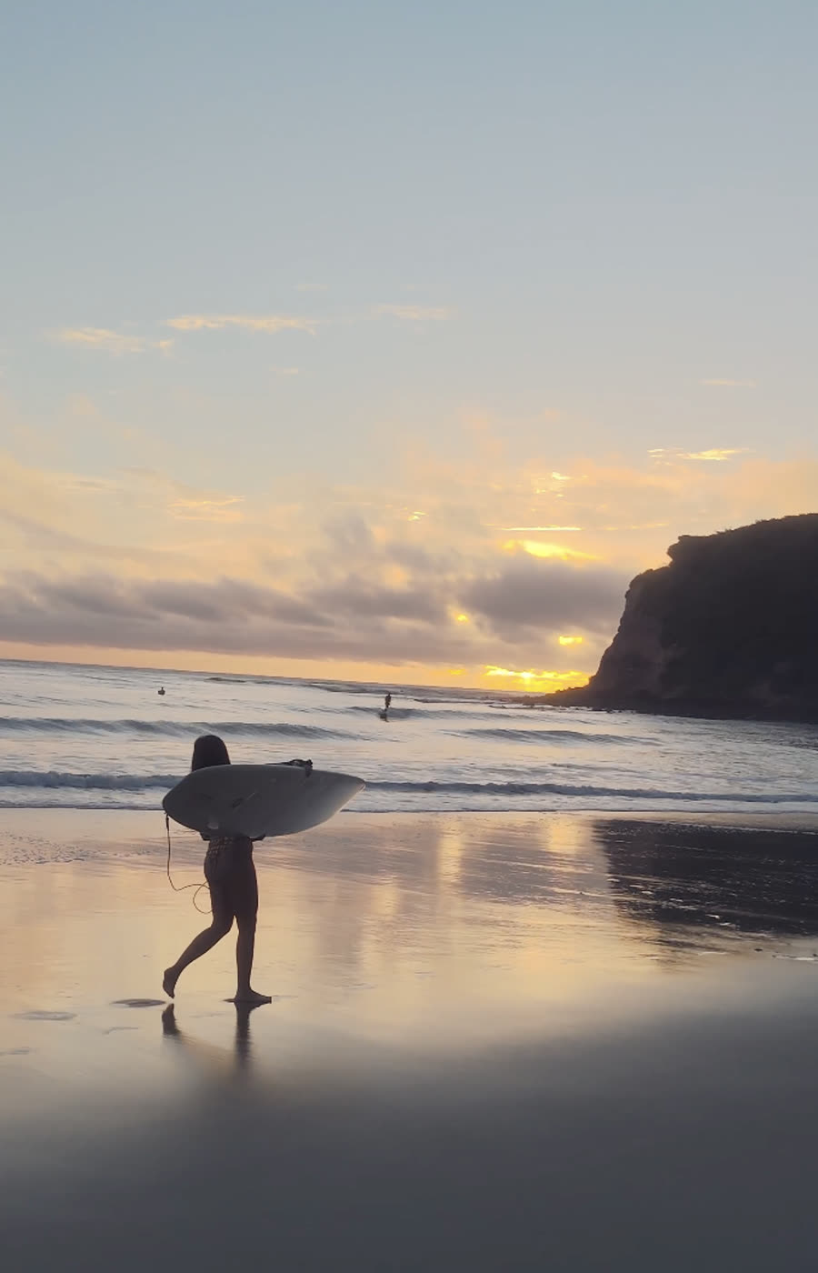 Surfeuse rentrant sur la plage au coucher de soleil