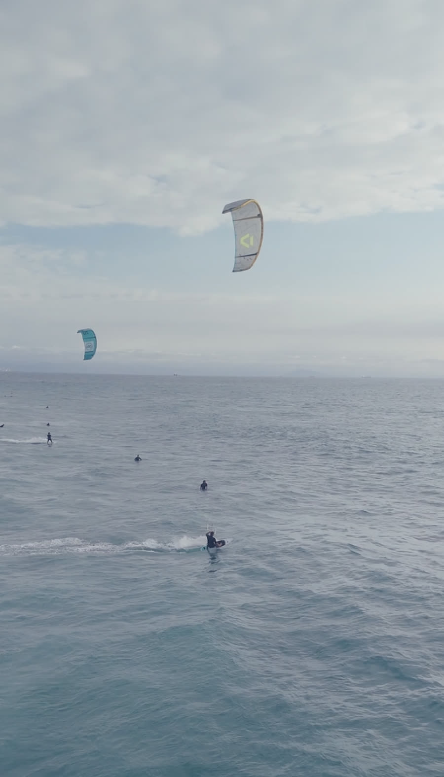 Deux kites dans le ciel au-dessus des surfeurs